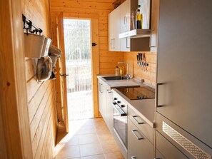 Una cocina moderna con paredes de madera, electrodomésticos de acero inoxidable y una vista a través de un ventanal.