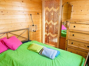 Une pièce en bois avec un lit, une commode et une prise de courant fixée au mur.