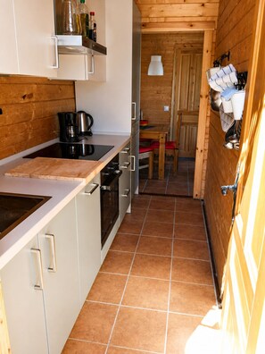 Une cuisine compacte équipée d’une cuisinière, d’un évier et de placards, qui donne sur un coin repas avec une table et des chaises.