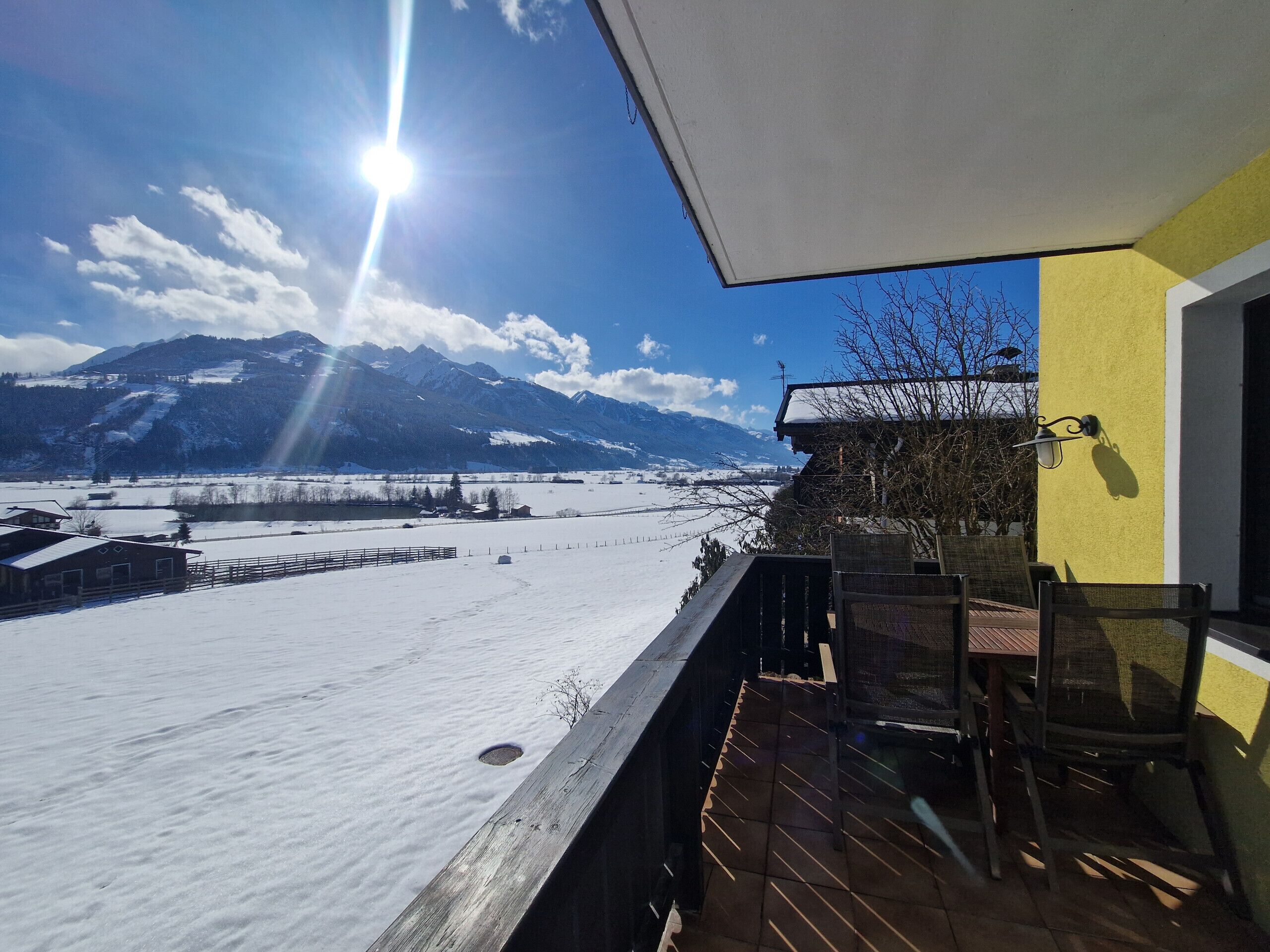 Ein Balkon mit Blick auf verschneite Felder und Berge.
