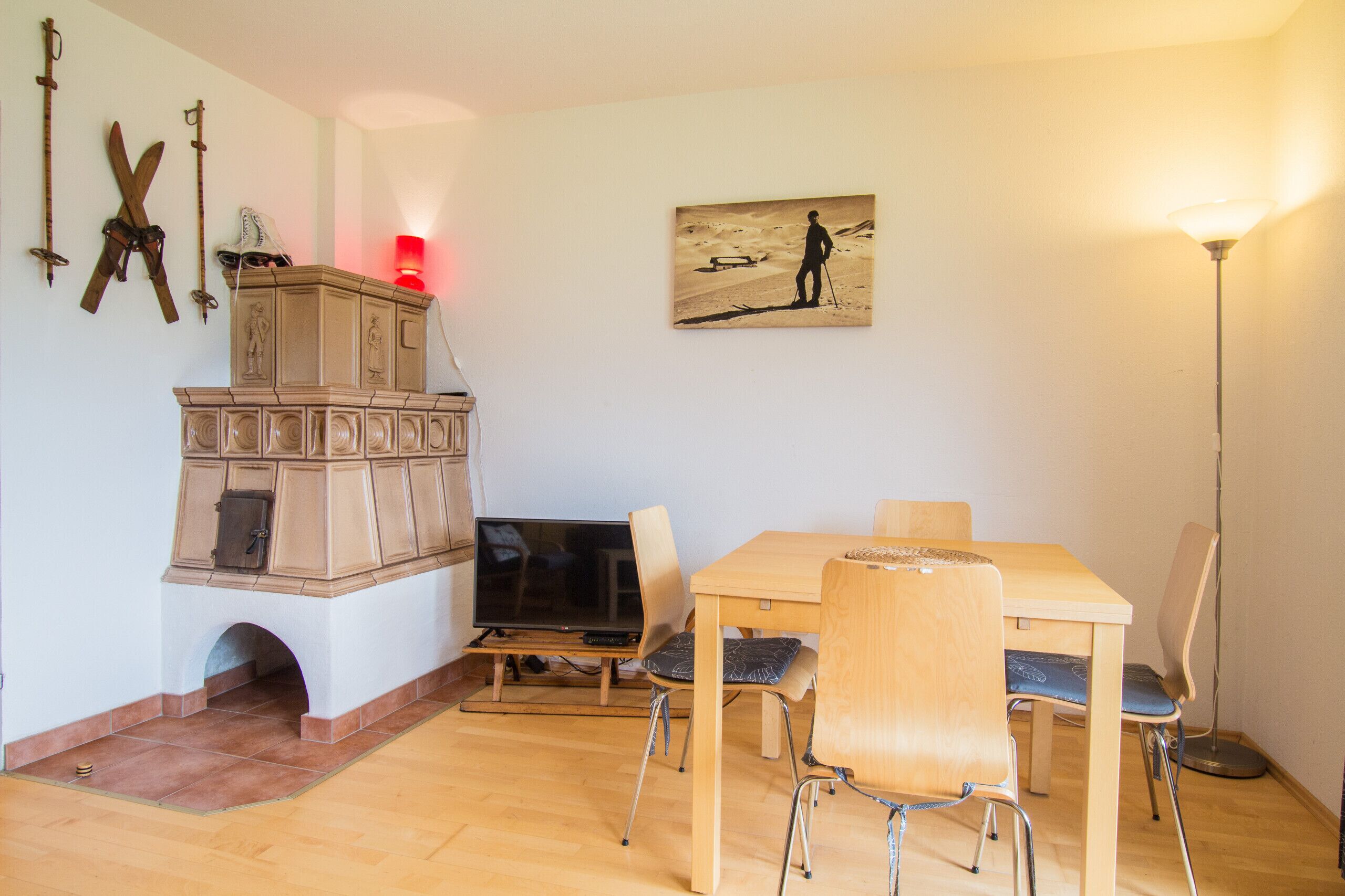 A dining area with a wooden table and chairs, a television, and a cabinet with decorative items.
