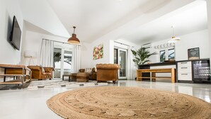 Een moderne woonkamer met een groot geweven vloerkleed, een bruine leren bank en een houten salontafel.