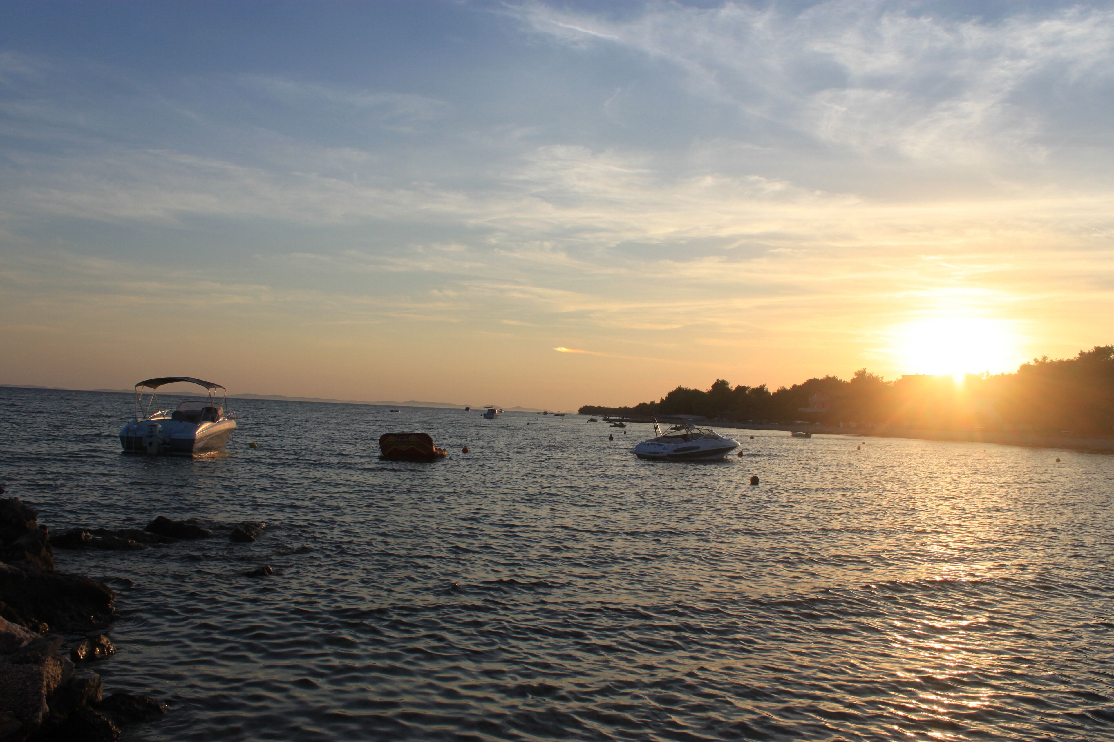 Un plan d'eau calme, avec des bateaux et un coucher de soleil.