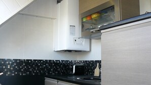 Een keuken met een zwart aanrecht, witte kasten en een betegelde spatwand.