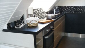 Een moderne keuken met een zwart aanrecht, roestvrijstalen apparatuur en een betegelde spatwand.
