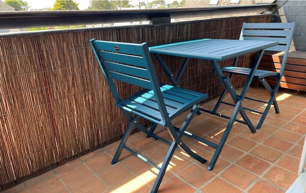 A patio with a blue metal table and chairs, a bamboo fence, and a tiled floor.