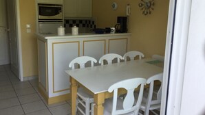 A compact kitchen with a microwave, a coffee maker, and a telephone on the counter. There is a dining table with four chairs. - House 2 bedrooms Pierre et Vacances Port Bourgenay Domaine du Moulin (Talmont -Saint-Hilaire)