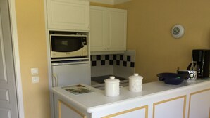 A kitchen with white cabinets, a microwave, a stove, and a coffee maker. - House 2 bedrooms Pierre et Vacances Port Bourgenay Domaine du Moulin (Talmont -Saint-Hilaire)