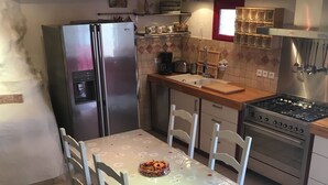 A kitchen with a refrigerator, stove, sink, and dining table with chairs. - House "Ciboulette (Mirabel-aux-Baronnies)