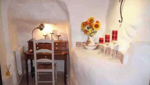 A room with a wooden desk, a chair, a lamp, a vase with flowers, and candles on a table. - House "Ciboulette (Mirabel-aux-Baronnies)