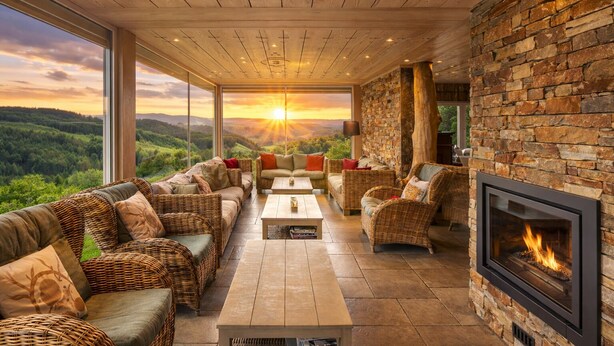 A modern living room with a fireplace, large windows, and a view of the landscape.