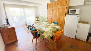 A compact kitchen with a dining table, chairs, a microwave, and a refrigerator.