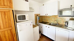 A compact kitchen with a microwave, a small refrigerator, a sink, and a coffee maker.