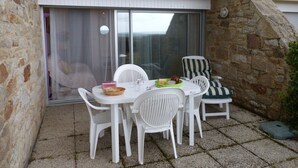 Un patio con una mesa y sillas, un muro de piedra y una puerta corrediza de vidrio.