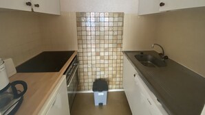 Una cocina compacta con estufa, pileta y salpicadero de azulejos.