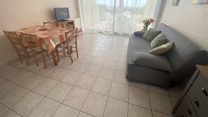 Una sala de estar con una mesa de comedor, sillas, un sofá y un televisor.