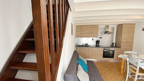 A modern kitchen with wooden cabinets, a dining table, and a bench with cushions. - KERNEVEST - Jardin, Tennis, Plage 600m - DT185 (Saint-Philibert)