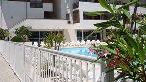 A modern hotel with a pool area, white railings, and a view of the building's architecture.