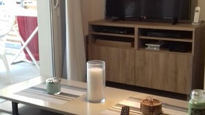 A living room with a TV, a glass of milk, a remote control, and a candle on a table.