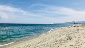 Une plage avec une eau d’un bleu limpide et un rivage sablonneux.
