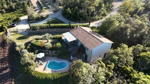 Une maison avec une piscine, entourée d’arbres et d’un mur de pierre.