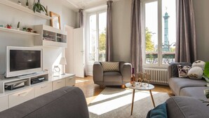 A modern living room with a flat-screen TV, sofa, and a coffee table with wine glasses. - ❤️❤️Paris Center Bastille Magnificient view Flat 3 rooms 2 bedrooms (Paris)