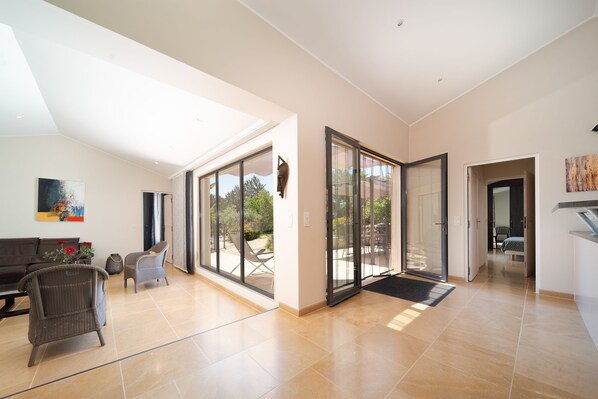 A spacious living area with a sofa, chairs, and a dining table. There is a sliding glass door leading to an outdoor patio.