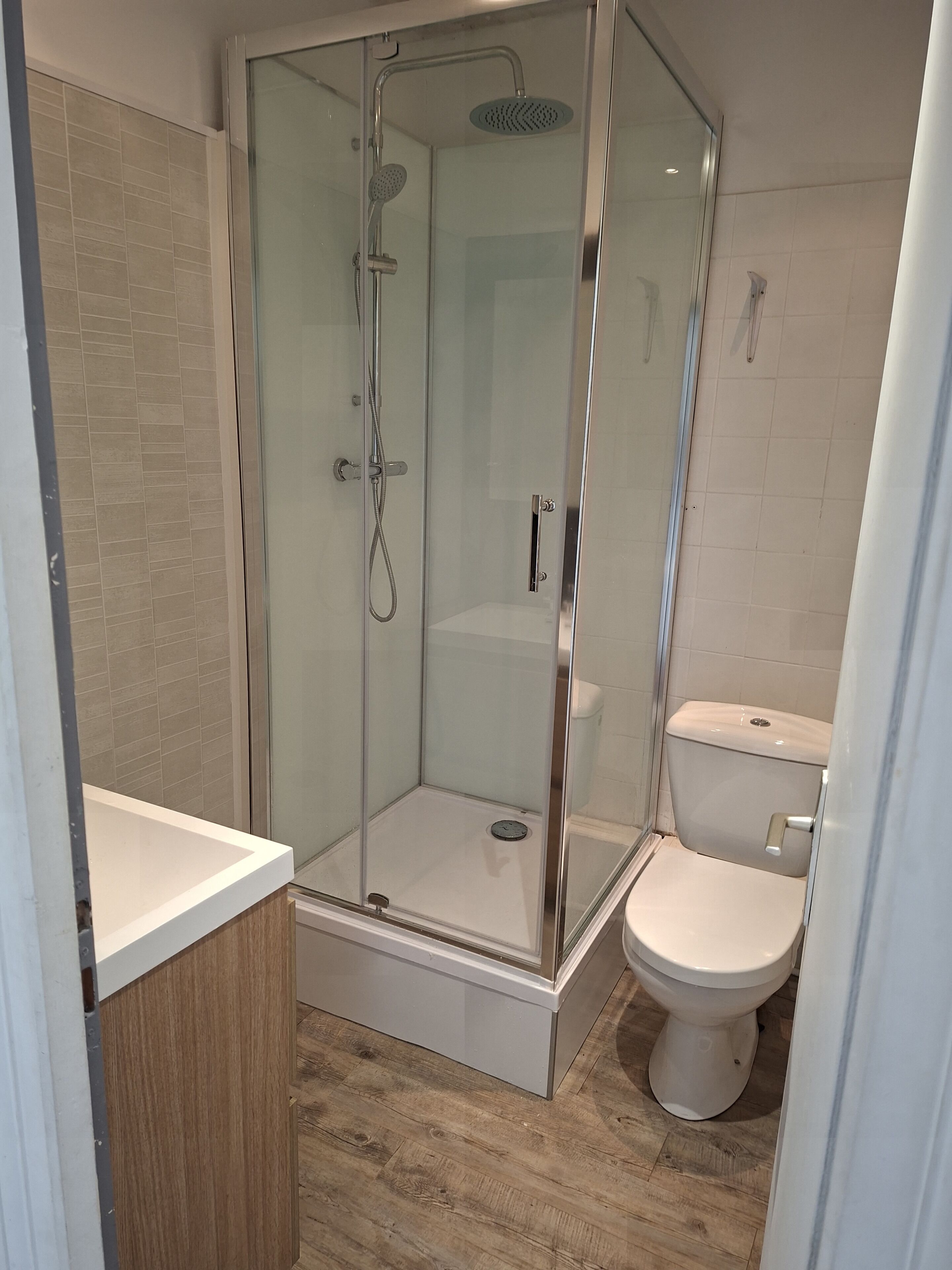 Ein modernes Badezimmer mit einer gläsernen Duschkabine, einer Toilette und einem Holzbadezimmer-Möbel.