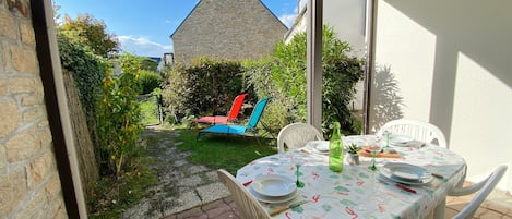 An outdoor patio with a table set for dining, a stone building in the background, and a clear sky.