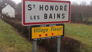 Señal de St Honoré les Bains con una señal amarilla de la D985 encima.