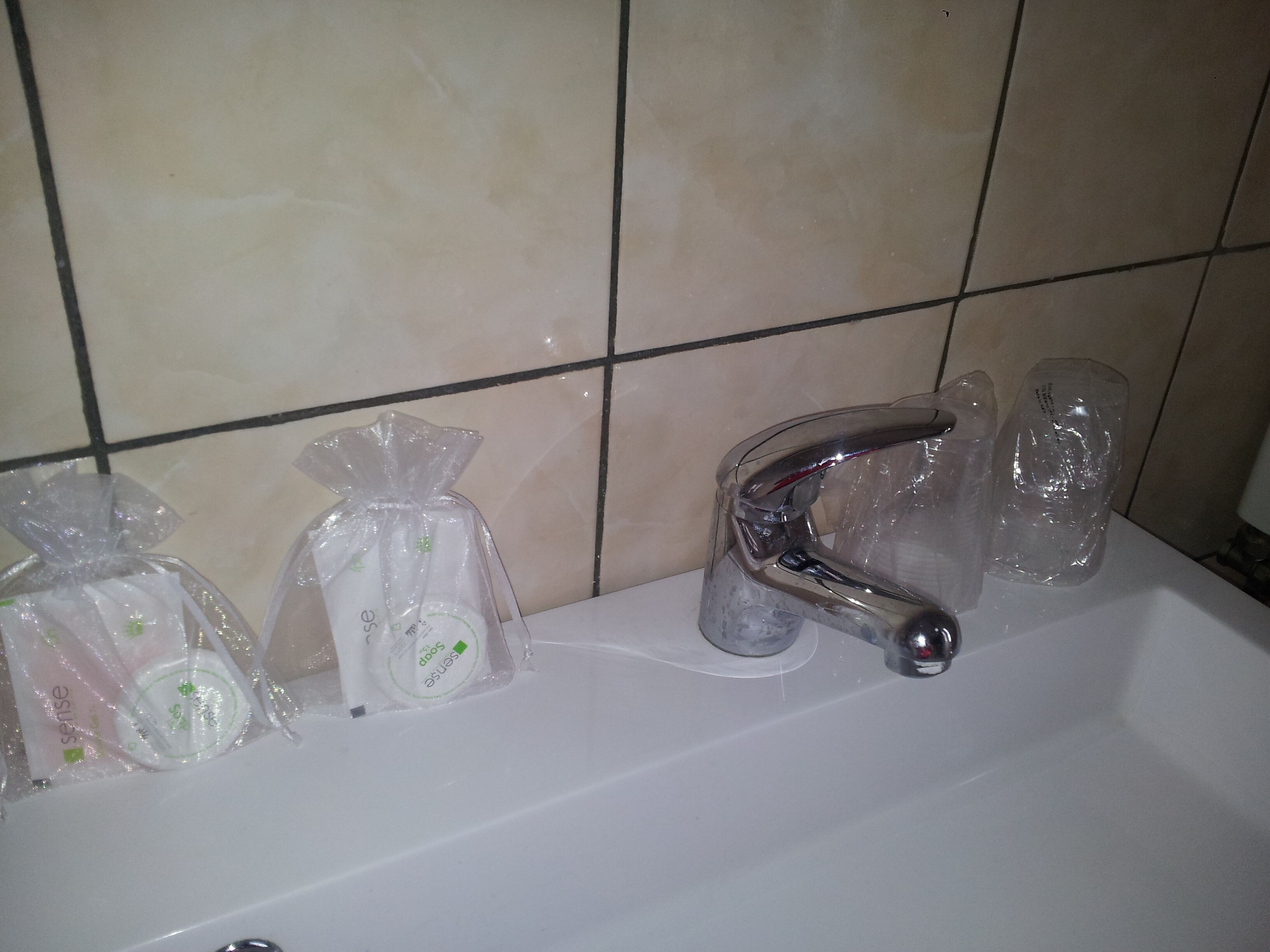 A bathroom sink with a chrome faucet and three plastic bags on the counter.