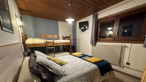 A dormitory room with a bunk bed, a single bed, a wall-mounted TV, and a window with curtains. - L'Eterle de Motzon en Bauges: in the mountains, snow, skiing, hiking, relaxation... (Aillon-le-Jeune)