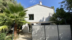 Ein modernes, zweistöckiges Haus mit flachem Dach, einem sichtbaren Schornstein und einem befestigten Eingangsbereich.