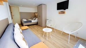 Ein modernes Schlafzimmer mit einem Bett, einer Couch, einem Kleiderschrank und einem an der Wand befestigten Fernseher.