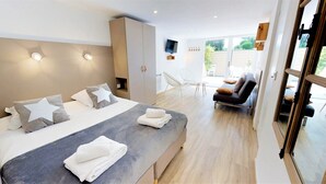 Ein modernes Schlafzimmer mit einem großen Bett, einer Couch und einem Fernseher.