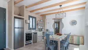 Eine moderne Küche mit integriertem Kühlschrank, Backofen und Geschirrspüler. Ein Esstisch mit Stühlen und einer Pendelleuchte sind ebenfalls vorhanden.