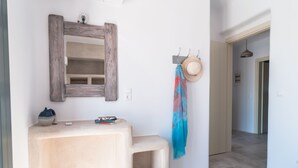 Ein Badezimmer mit einem spiegelnden Holzelement, einem beigefarbenen Waschtisch und einem Handtuch an einem Haken.