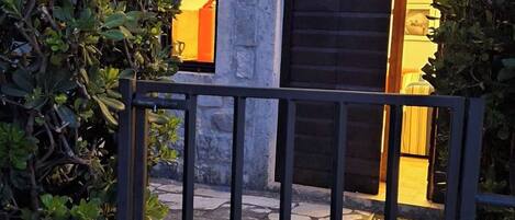 A stone building with a metal gate, a balcony, and a window with a closed shutter.