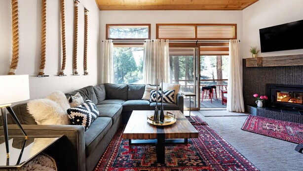 A modern living room with a wooden ceiling, a sectional sofa, a coffee table, and a fireplace.