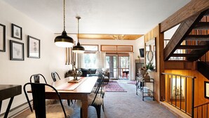 A dining area with a wooden table and chairs, a chandelier, and a staircase with wooden railings.