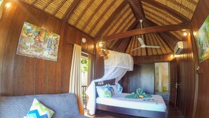 Een kamer met een bed, een slaapbank, een plafondventilator en een muurschildering.
