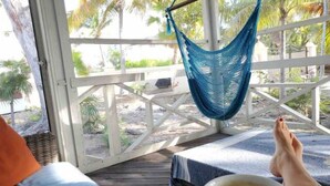 A hammock chair, a wooden deck, and a view of palm trees. - Gated Villa w Private Pool, Outdoor Shower, BBQ • Easy Walk to GraceBay Beach (Providenciales)