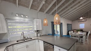 A modern kitchen with white cabinetry, a large island, and pendant lighting. - Gated Villa w Private Pool, Outdoor Shower, BBQ • Easy Walk to GraceBay Beach (Providenciales)