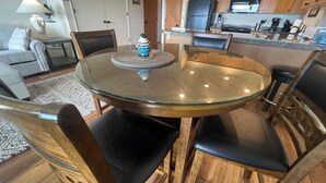 A dining area with a round glass table surrounded by wooden chairs. - On the Promenade 1st floor. Spectacular Panoramic Ocean Views, Patio with grassy (Seaside)