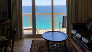 A living room with a large sliding glass door leading to a balcony with a view of the ocean. - GULF FRONT!!  Beautiful Sweeping Views! Tiki Bar, Deli, 3 pools, LOCATION (Destin)
