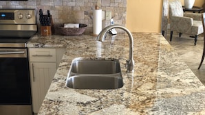 A kitchen with granite countertops, stainless steel appliances, and a double sink. - GULF FRONT!!  Beautiful Sweeping Views! Tiki Bar, Deli, 3 pools, LOCATION (Destin)