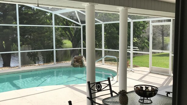 Un patio couvert avec une piscine, du mobilier d’extérieur et un ventilateur de plafond.
