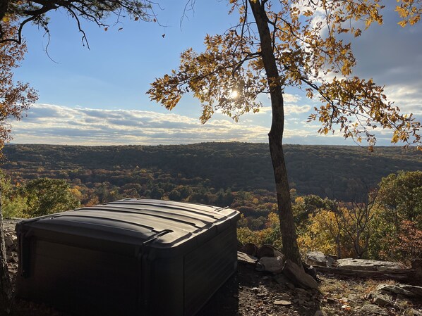 A tent in a forested area with a view of a valley.