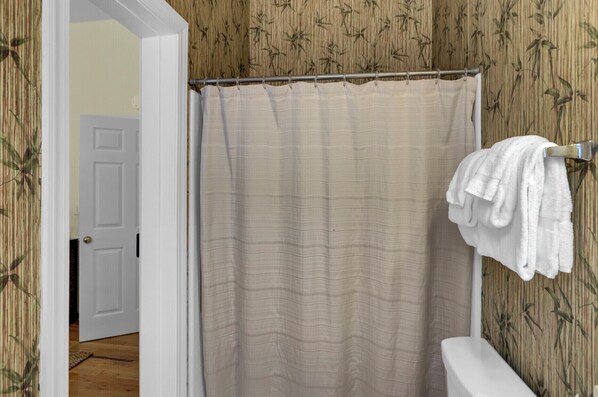 A bathroom with a bamboo-patterned wall, a beige shower curtain, and a white toilet. - Award-Winning Resort Amenities | Grand Pavilion 17 (Isle of Palms)
