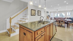 A kitchen with a central island, wooden cabinets, and pendant lighting. - Award-Winning Resort Amenities | Beach Club Villa 12 (Isle of Palms)